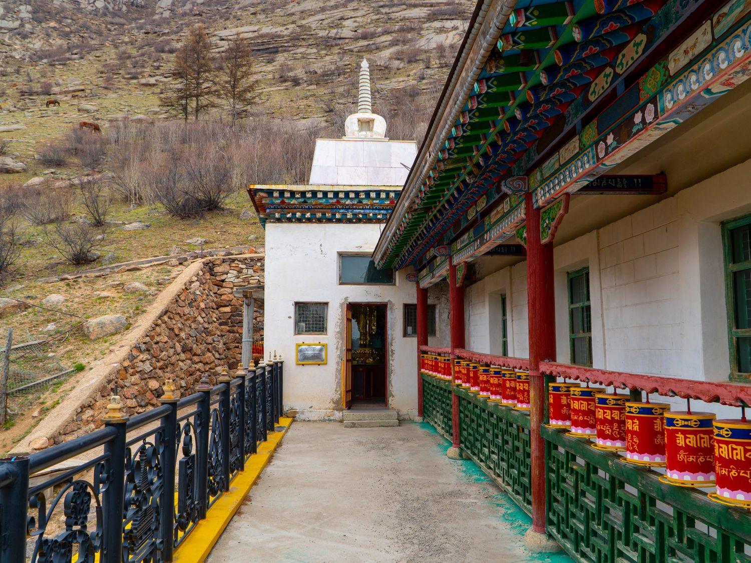 Buddhist temple with a white stupa and red prayer wheels in the hills of Central Mongolia