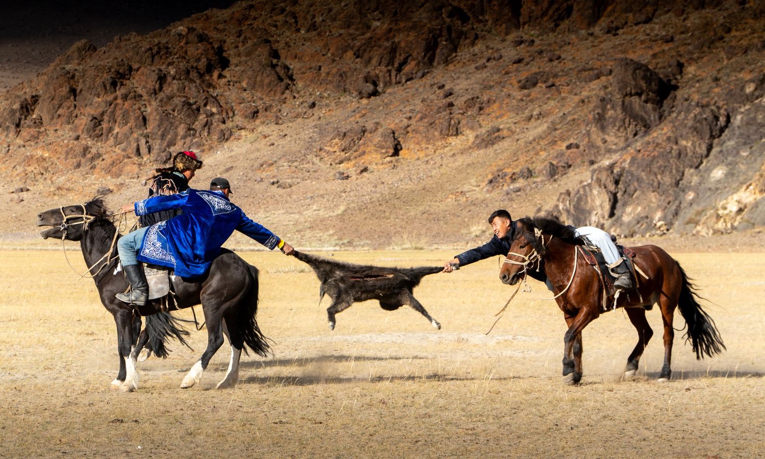 Two riders pulling a goat skin in the kokpar horseback game at the festival